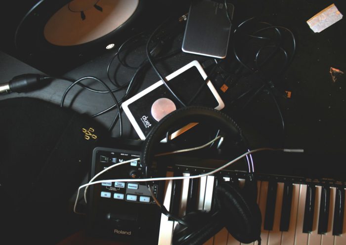 flat-lay photo of headphones, MIDI keyboard, and speaker on black surface